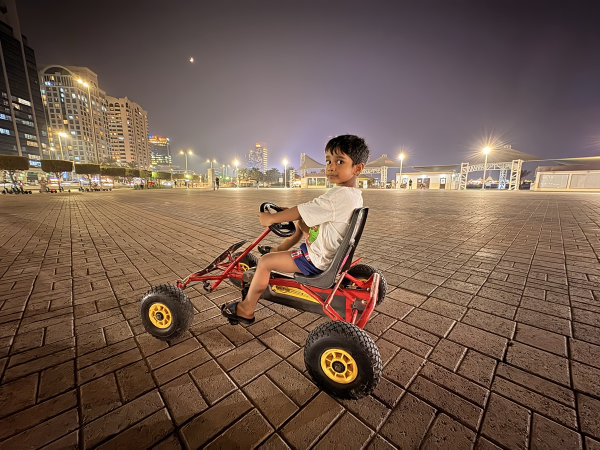 Dhyanchand riding a go-kart at night with city lights behind him